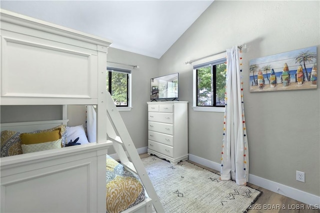 bedroom featuring lofted ceiling, multiple windows, light wood-style floors, and baseboards