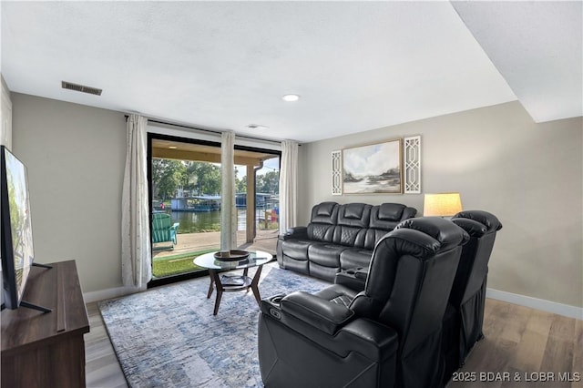 living room featuring visible vents, baseboards, and light wood-style flooring