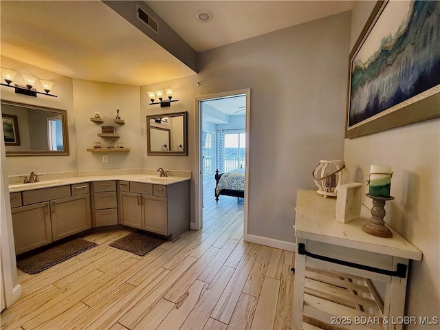 bathroom with a sink, visible vents, wood finished floors, and double vanity