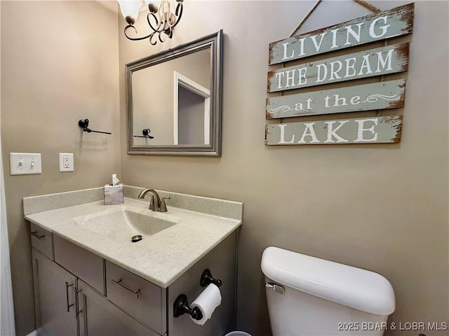 half bathroom featuring toilet, a chandelier, and vanity