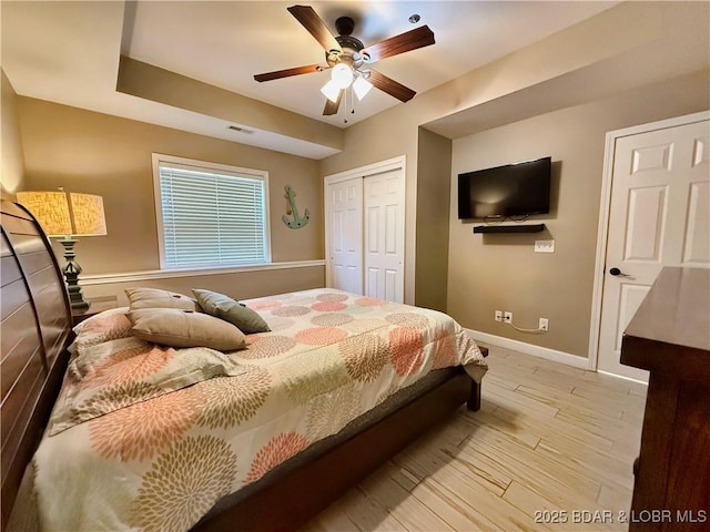 bedroom with visible vents, light wood-style flooring, a closet, baseboards, and ceiling fan