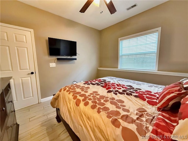 bedroom with a ceiling fan, visible vents, light wood finished floors, and baseboards