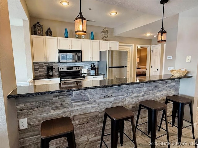 kitchen with a breakfast bar area, backsplash, visible vents, and appliances with stainless steel finishes