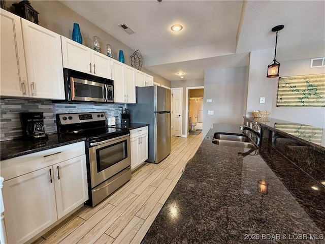 kitchen featuring visible vents, backsplash, wood finish floors, stainless steel appliances, and a sink