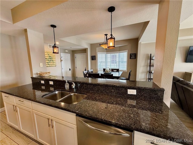 kitchen featuring dishwasher, dark stone counters, white cabinets, a textured ceiling, and a sink