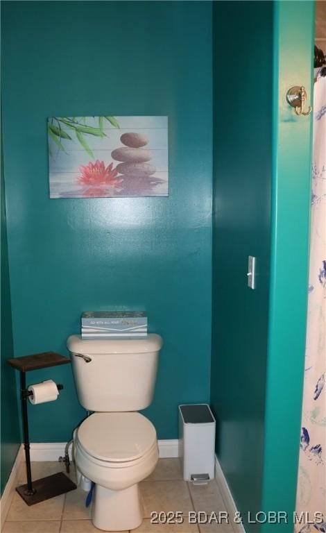 bathroom featuring tile patterned flooring, toilet, a shower with curtain, and baseboards