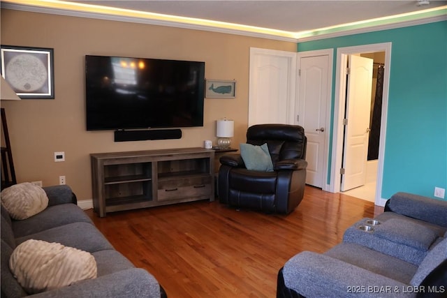 living area with wood finished floors, baseboards, and ornamental molding