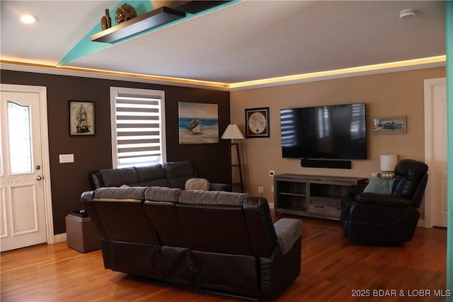 living area with a wealth of natural light, wood finished floors, and crown molding