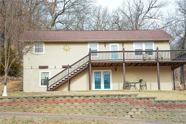 rear view of house featuring a deck, stairway, and roof with shingles