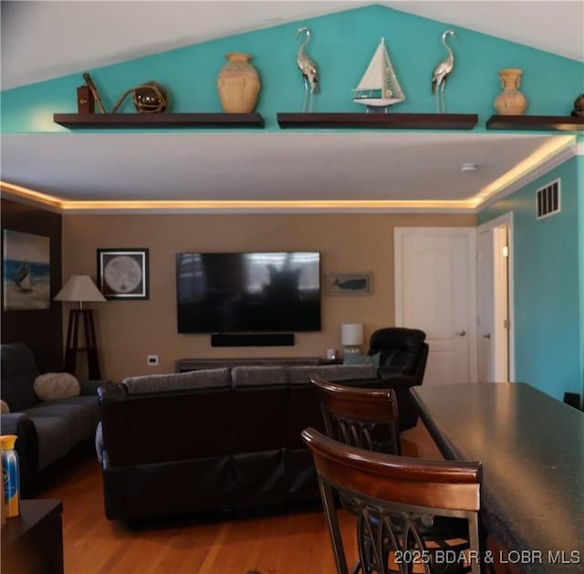 living room featuring visible vents, lofted ceiling, and wood finished floors