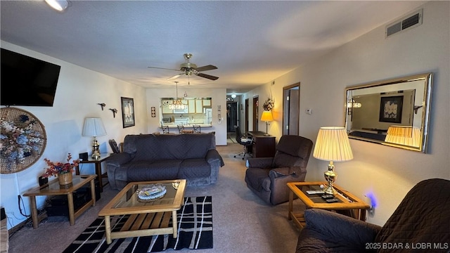 living area featuring visible vents, carpet floors, and ceiling fan