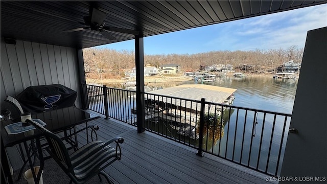 deck with a water view, ceiling fan, and a dock