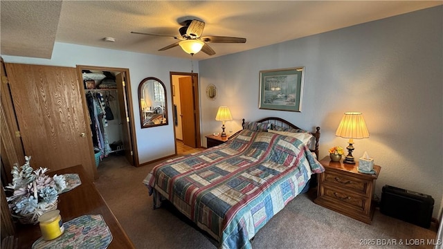 bedroom featuring a ceiling fan, carpet, a spacious closet, a closet, and a textured ceiling