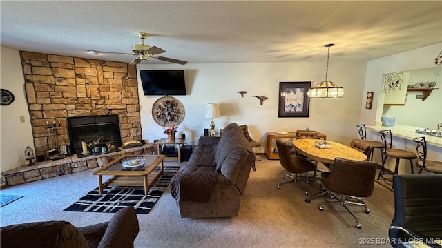 carpeted living area with a fireplace, a textured ceiling, and ceiling fan