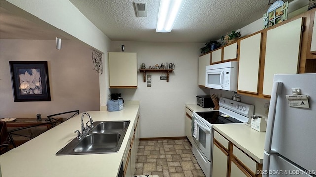 kitchen with a sink, white appliances, a peninsula, and light countertops