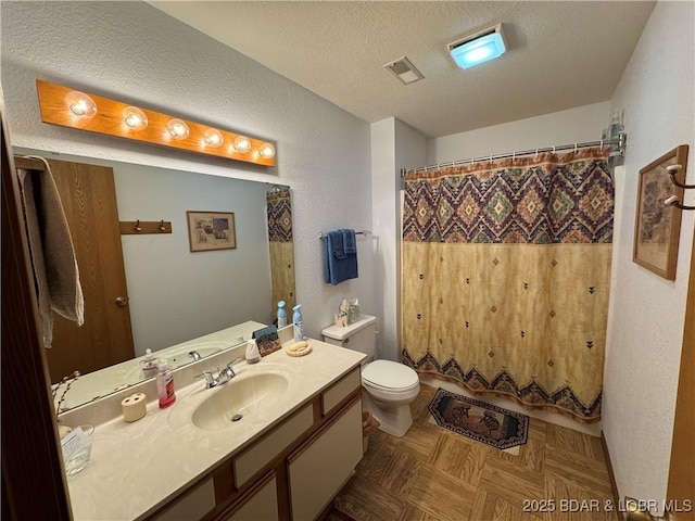 bathroom featuring visible vents, a textured ceiling, vanity, and toilet