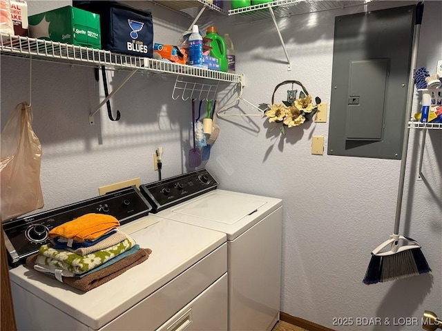 laundry room featuring laundry area, electric panel, a textured wall, and washer and clothes dryer