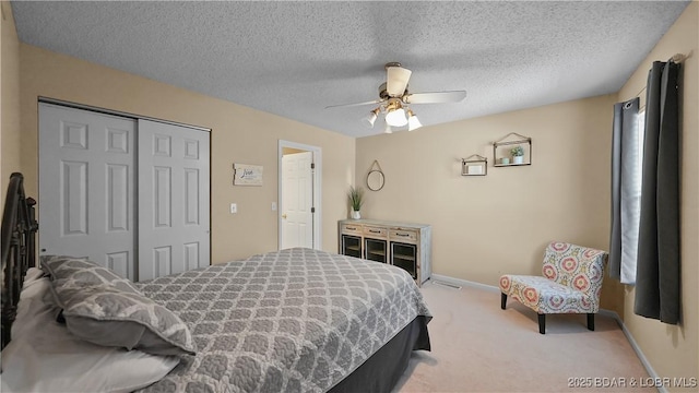 bedroom featuring a closet, a textured ceiling, carpet flooring, and a ceiling fan