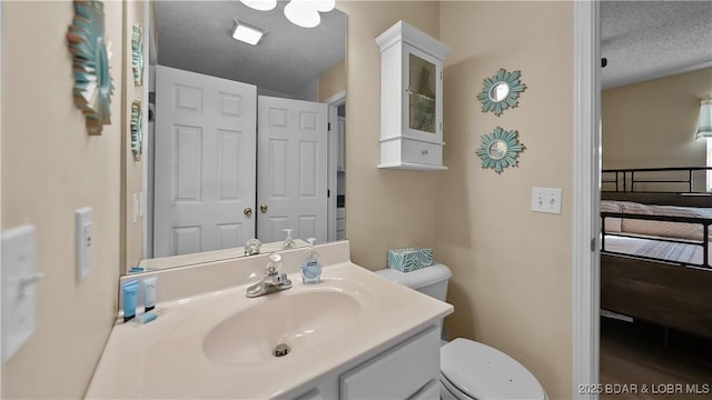 bathroom with a textured ceiling, vanity, and toilet