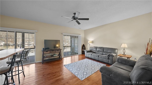 living room featuring wood finished floors, baseboards, and ceiling fan