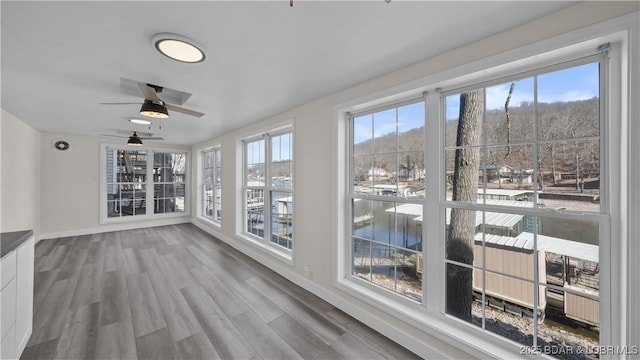 unfurnished sunroom featuring a healthy amount of sunlight and a ceiling fan