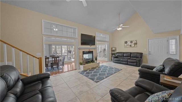 tiled living area featuring stairway, high vaulted ceiling, ceiling fan, and a fireplace