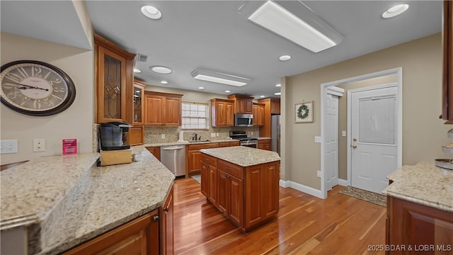 kitchen with a sink, light wood-style flooring, brown cabinets, and stainless steel appliances