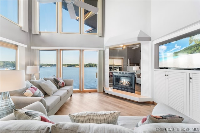 living room with a glass covered fireplace, wood finished floors, and a ceiling fan