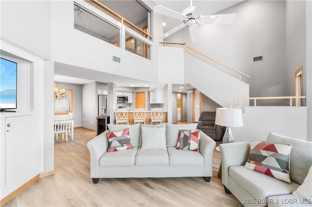 living area with ceiling fan with notable chandelier, visible vents, and light wood finished floors