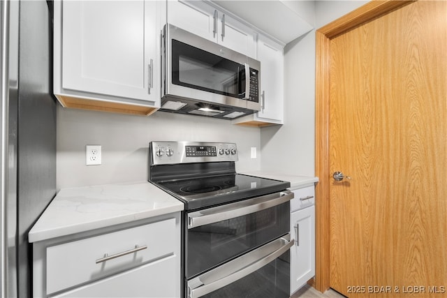 kitchen featuring white cabinets, light stone counters, and appliances with stainless steel finishes