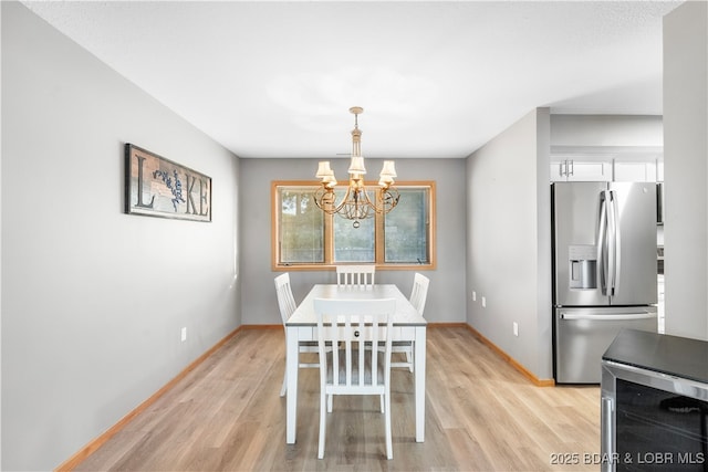 dining room with an inviting chandelier, beverage cooler, light wood-style floors, and baseboards