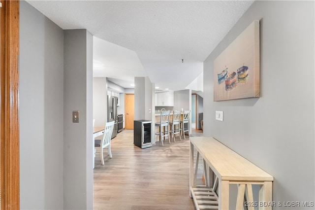 hallway with light wood-type flooring and a textured ceiling