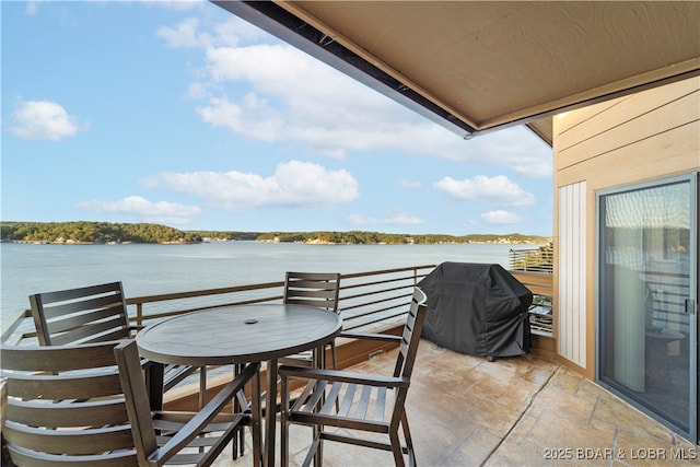 balcony with outdoor dining area, a water view, and a grill