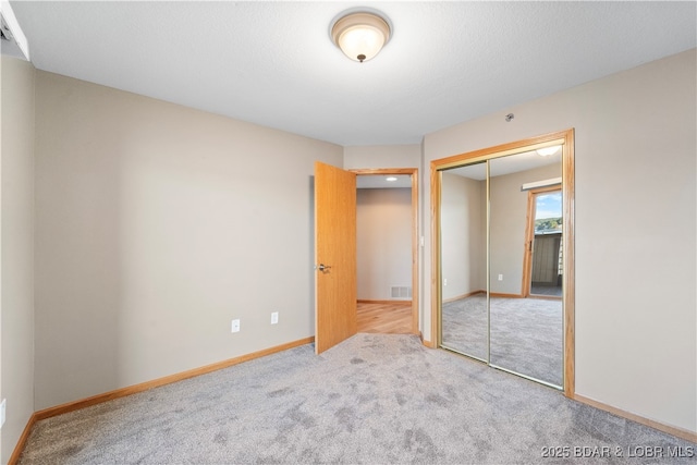 unfurnished bedroom with a closet, baseboards, carpet, and visible vents