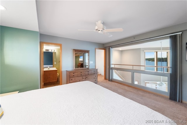 unfurnished bedroom with connected bathroom, a water view, ceiling fan, and carpet floors