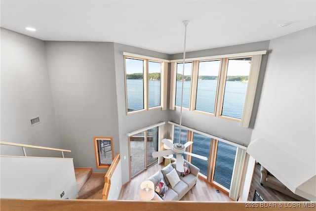 dining room with visible vents, a water view, a healthy amount of sunlight, and wood finished floors