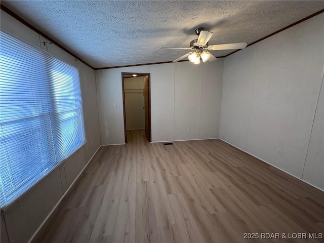 spare room with visible vents, a textured ceiling, wood finished floors, crown molding, and ceiling fan