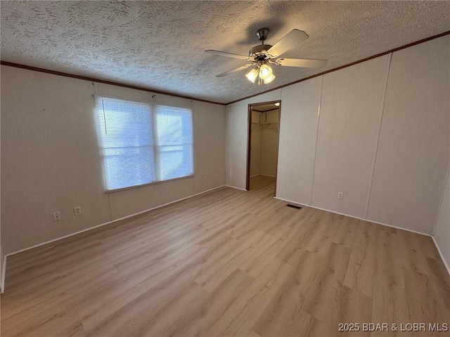 unfurnished bedroom with a textured ceiling, a ceiling fan, light wood finished floors, and ornamental molding