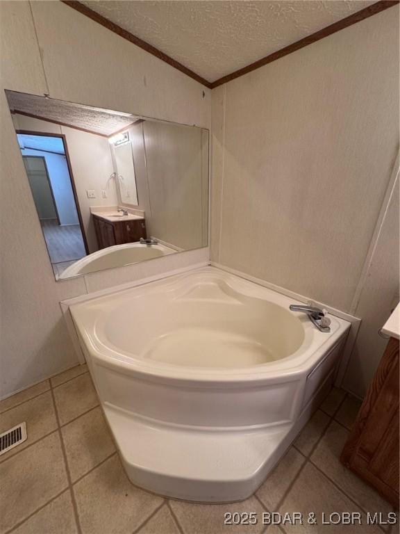 full bathroom featuring visible vents, a textured ceiling, vanity, and a garden tub