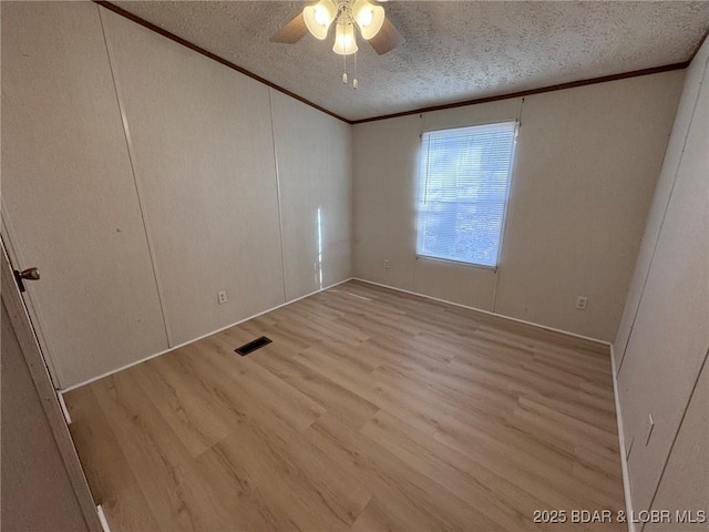 unfurnished bedroom with visible vents, ornamental molding, wood finished floors, a textured ceiling, and a ceiling fan