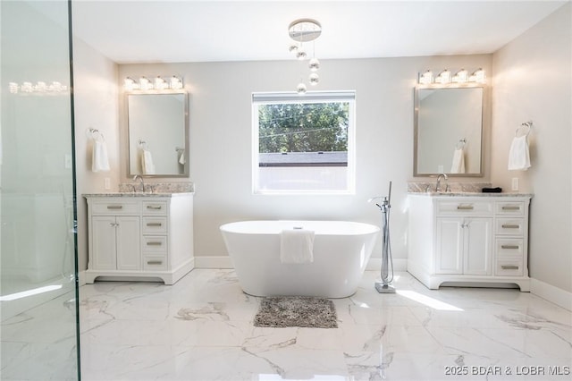 full bath featuring baseboards, a soaking tub, two vanities, a sink, and marble finish floor