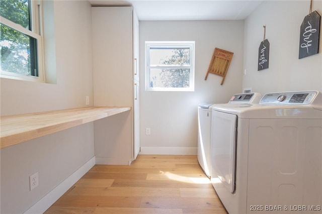 washroom featuring washer and dryer, light wood-type flooring, baseboards, and laundry area