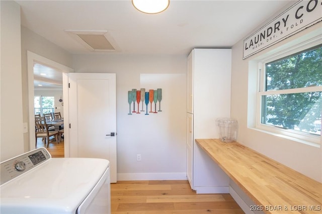 washroom with light wood-type flooring, cabinet space, baseboards, washer / dryer, and attic access