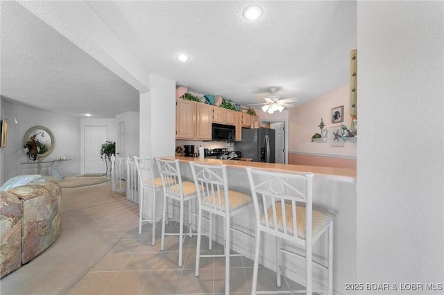 kitchen with a textured ceiling, black appliances, and a breakfast bar