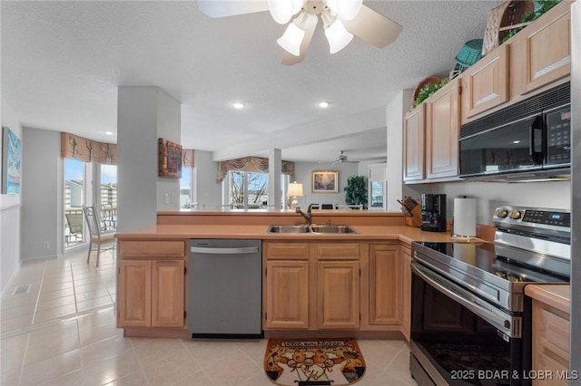 kitchen with a sink, appliances with stainless steel finishes, light tile patterned flooring, and a ceiling fan