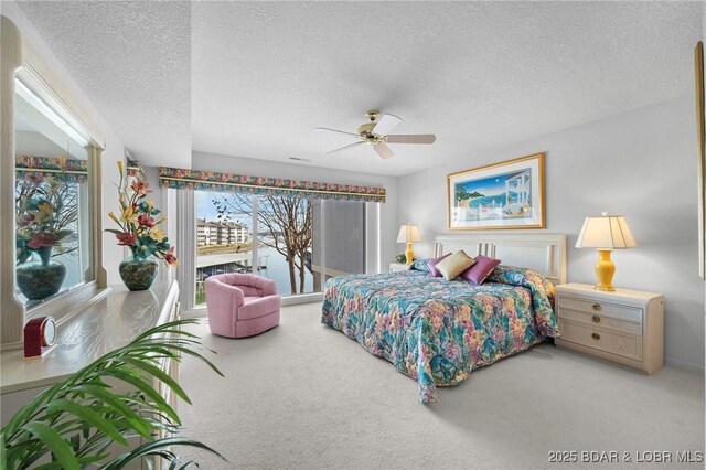 carpeted bedroom with access to outside, a ceiling fan, and a textured ceiling