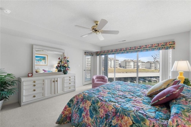 carpeted bedroom with visible vents, a textured ceiling, access to exterior, and a ceiling fan