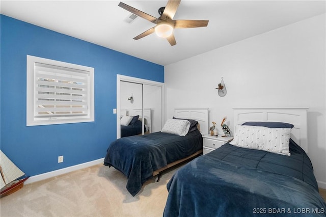 bedroom featuring a ceiling fan, light colored carpet, a closet, and baseboards