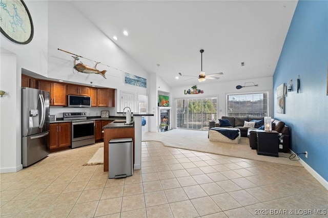 kitchen with dark countertops, open floor plan, stainless steel appliances, and light tile patterned floors