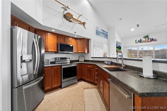 kitchen with a sink, dark countertops, light tile patterned floors, and stainless steel appliances